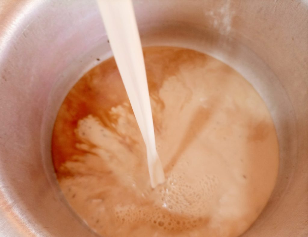 adding cups of milk to Ugandan chai tea